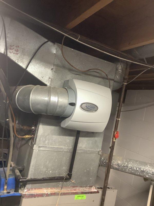 Completed estimate for replacement of customer-supplied furnace and air conditioning system. Assessed existing HVAC equipment location in basement utility area, including current furnace, ductwork configuration, and humidifier setup. Evaluated installation requirements for new equipment, noting existing sheet metal plenum connections, cylindrical ductwork with elbow configuration, and copper refrigerant line routing. Documented current system layout and mechanical room conditions to provide accurate installation proposal for self-supplied equipment to be purchased through Famous Supply.