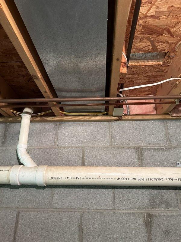 Installed dedicated electrical circuit for tankless water heater system in basement utility area. Routed conduit and wiring through exposed floor joists alongside existing plumbing infrastructure, ensuring proper clearances from PVC drain lines and copper water supply pipes. Circuit installation completed and ready for tankless unit connection and final inspection.