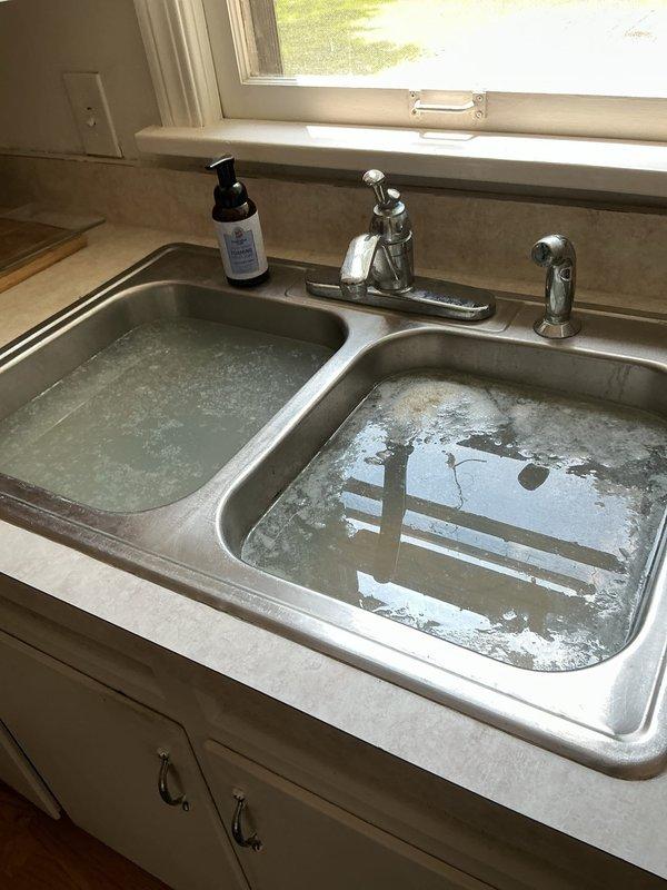 Responded to multiple plumbing issues including kitchen sink backup connected to garbage disposal and master bathroom sink drainage problems. Cleared blockages in drain lines and verified proper flow through disposal system. Kitchen sink showed standing water in both basins, indicating main drain obstruction that was successfully cleared. Addressed master bath sink drainage by clearing P-trap and drain assembly. Repaired leaking exterior hose bib by replacing worn washer and tightening packing nut. Inspected basement plumbing infrastructure, noting aging cast iron drain lines with surface corrosion. All fixtures tested and confirmed operational upon completion.