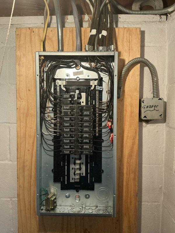 Replaced existing 100 amp electrical panel with new unit and installed exterior 100 amp disconnect on brick wall. Extended waterline grounding conductor to new disconnect location to ensure proper system bonding. Verified existing grounding infrastructure including visible ground rods and hot water tank bonding for code compliance. Installed white PVC conduit from exterior disconnect down brick wall for weather protection. Organized and terminated all branch circuit wiring within new interior panel, arranging circuit breakers in dual columns. Routed service conductors through gray conduit from panel to exterior disconnect. Single technician completed full installation over one work day after parts arrived at shop.