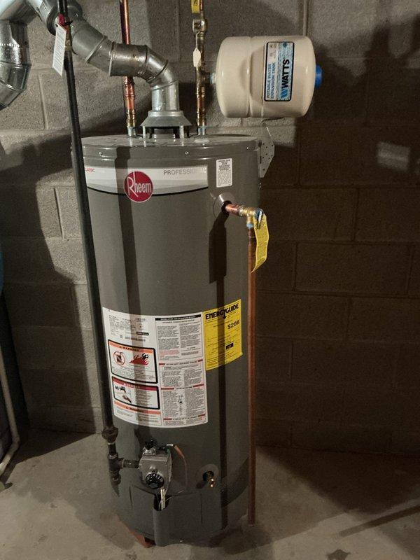 Responded to service call for leaking water heater. Upon arrival, performed diagnostic inspection of residential tanked water heater located in basement utility area. Confirmed active leak originating from bottom of tank, indicating internal tank failure. Water heater identified as Rheem Professional Series unit of unknown age with significant corrosion and deterioration at base. Documented equipment condition with photographs showing compromised tank integrity, existing plumbing connections including copper supply lines, temperature and pressure relief valve, expansion tank, and proximity to HVAC furnace system. Advised customer that bottom tank leaks are non-repairable and require complete water heater replacement due to structural failure of inner tank lining. Provided replacement options and recommendations for new installation.