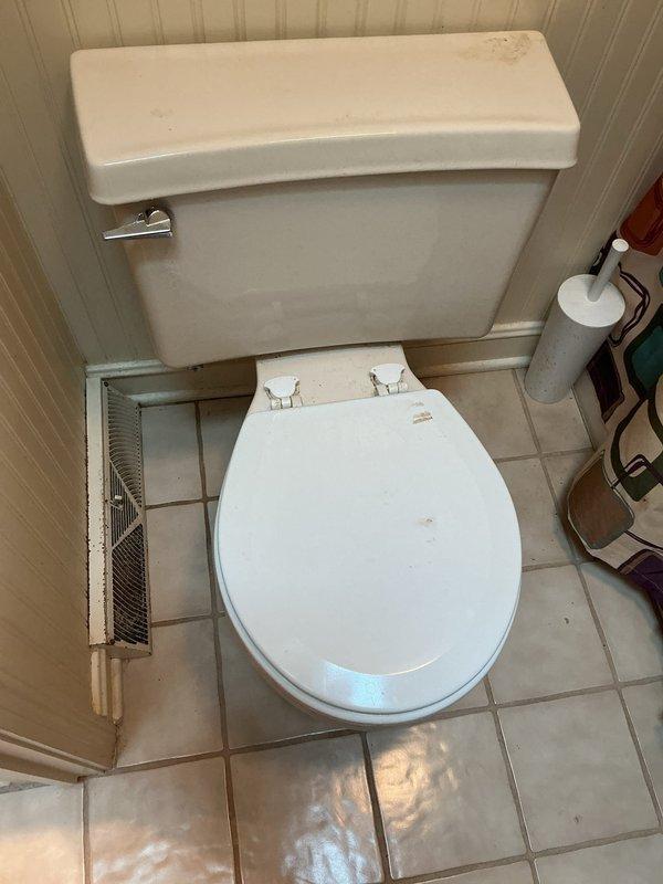 Completed toilet replacement in residential bathroom of home built in 1981. Removed existing toilet fixture and installed new white ceramic toilet with standard two-piece design, chrome flush lever, and white seat. Connected water supply line to wall-mounted chrome shut-off valve and verified proper operation with no leaks. Tested flush mechanism for proper function and ensured secure mounting to tile floor.