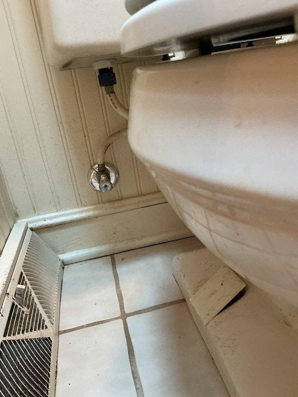 Completed toilet replacement in residential bathroom of home built in 1981. Removed existing toilet fixture and installed new white ceramic toilet with standard two-piece design, chrome flush lever, and white seat. Connected water supply line to wall-mounted chrome shut-off valve and verified proper operation with no leaks. Tested flush mechanism for proper function and ensured secure mounting to tile floor.