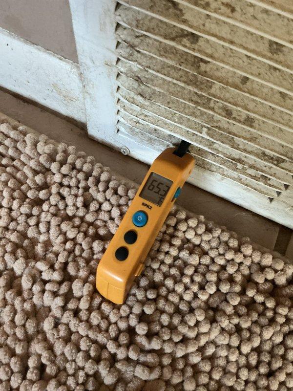 Completed MVP recurring cooling maintenance visit on residential HVAC system. Performed comprehensive system diagnostics including temperature differential measurements at supply register, recording 65°F air temperature at floor-level vent. Conducted electrical testing on outdoor condensing unit using digital multimeter, measuring 15.4 volts at system components to verify proper electrical operation. Inspected return air ventilation showing moderate dust accumulation on grille, typical for residential system requiring routine filter maintenance. All critical system parameters checked and operating within normal specifications for continued cooling performance.