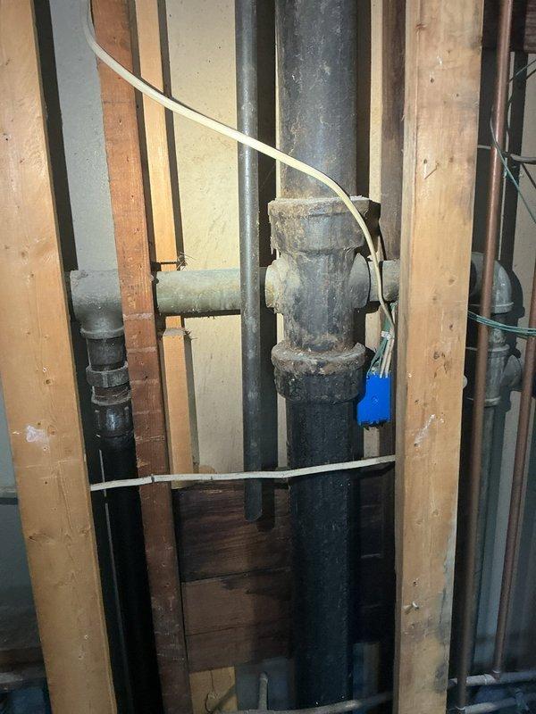 Responded to reported water leak from second floor plumbing into basement area. Upon inspection, identified aged cast iron waste stack with corroded T-junction fitting showing significant deterioration and dusty mineral buildup. The compromised fitting connection was determined to be the source of the leak penetrating through to the lower level. Documented existing plumbing infrastructure including vertical drain stack, associated fittings, and auxiliary supply lines for service records. Customer advised that potential third floor leak was not investigated at this time per their request.