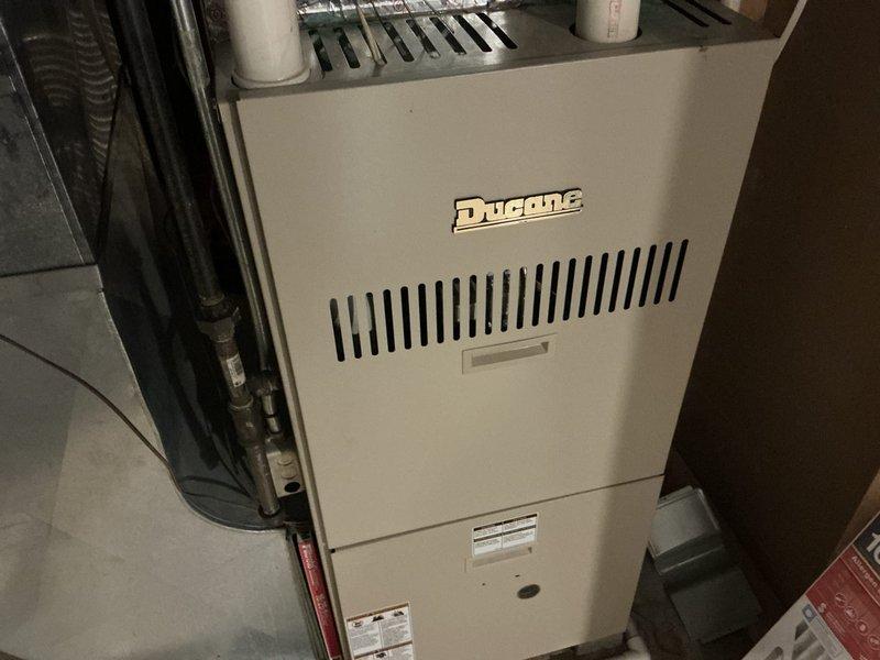 Completed furnace replacement estimate for an 18-year-old heating system with no cooling capability. Documented existing Duane-branded furnace unit with associated ductwork, PVC venting, gas piping with yellow shutoff valve, and black flexible ducting connections. Assessed mechanical room layout including all plumbing, ventilation components, and structural considerations for replacement equipment specifications.