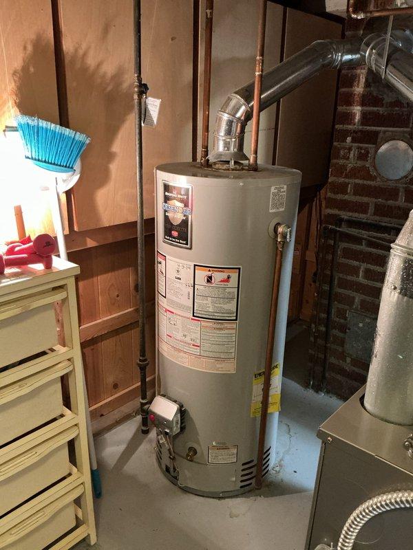 Conducted on-site assessment of existing 50-gallon gas water heater located in basement utility area for replacement estimate. Evaluated current installation including copper supply lines, gas connections, exhaust venting system with metallic flue pipe, and clearance specifications in confined space between wood-framed partition and exposed brick wall. Documented unit specifications, manufacturer information, and existing plumbing configuration with copper piping connections at top of unit. Photographed installation conditions, surrounding infrastructure, and access points to provide accurate replacement quote for new 50-gallon gas water heater with comparable specifications and code-compliant installation requirements.