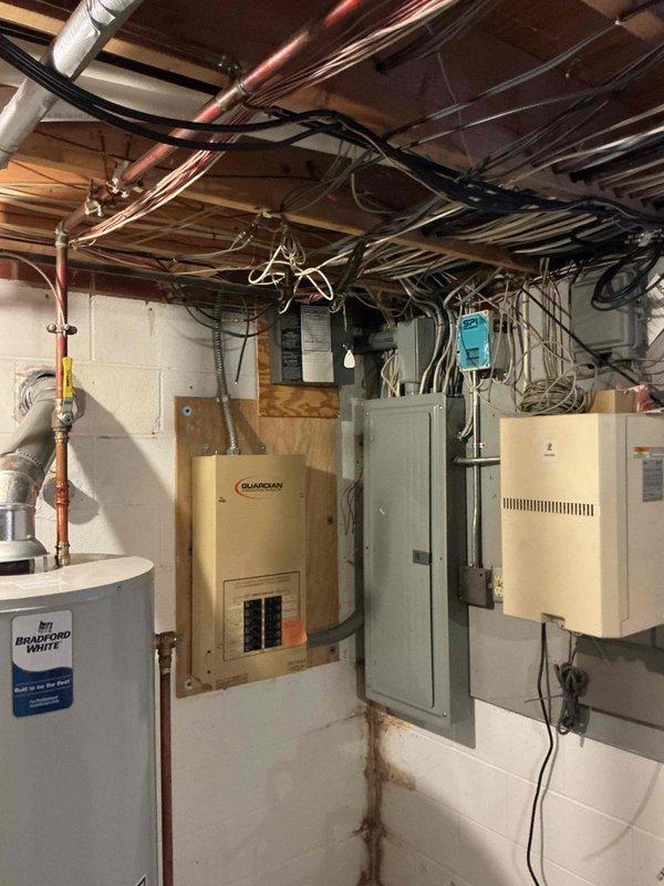 Conducted on-site evaluation for whole home backup generator installation in residential property with existing natural gas infrastructure. Assessed basement utility area containing Bradford White water heater, Guardian electrical transfer switch, main electrical service panel, and HVAC equipment to determine generator sizing requirements and installation feasibility. Documented existing electrical panel configuration with multiple branch circuits rated at 15 and 20 amps, reviewed current load distribution, and identified available connection points for generator integration. Property previously had generator system that was removed, with furnace, dryer, and stove currently operating on natural gas service. Evaluated electrical infrastructure, transfer switch compatibility, and utility room layout to develop comprehensive whole home backup power solution estimate.