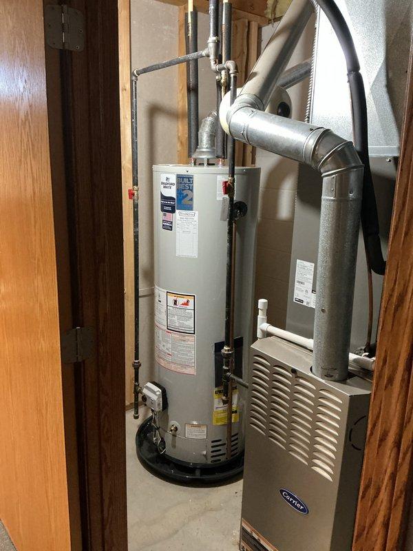 Removed and replaced existing water heater with new Bradford White 40-gallon tall model in residential utility room. Installation included new expansion tank and water shut-off valve to meet current plumbing code requirements. Connected copper supply lines and piping to unit, verified all connections for proper seal and operation. Unit is covered under 8-year manufacturer warranty with extended 2-year warranty for total 10-year coverage. Tested system for proper heating function, checked temperature and pressure relief valve operation, and confirmed no leaks at all connection points. Water heater installed adjacent to existing HVAC furnace unit in mechanical closet with adequate clearance for maintenance access.