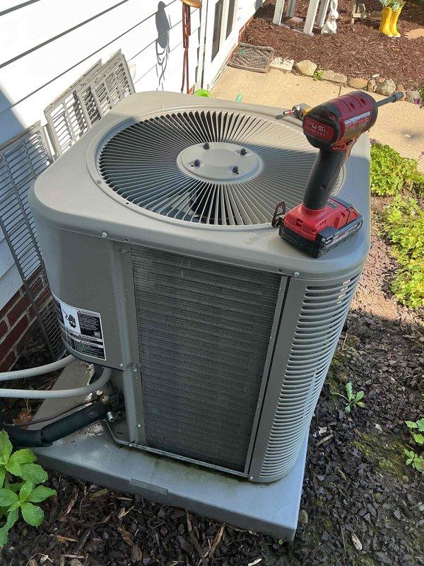 Completed preventive maintenance cooling visit on 4-year-old residential air conditioning system. Performed comprehensive inspection of outdoor condenser unit, including visual assessment of cabinet condition, refrigerant line connections, and electrical conduit routing. Unit found operating within normal parameters with proper airflow through cylindrical condenser coil and top-mounted fan assembly. Verified secure mounting on concrete pad and confirmed adequate clearance from building structure for optimal performance.