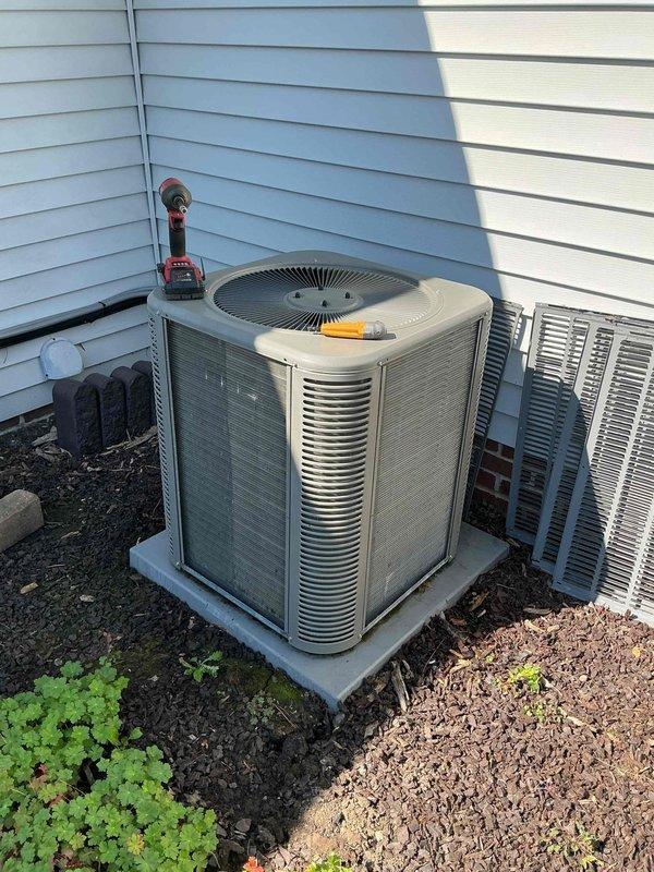 Completed preventive maintenance cooling visit on 4-year-old residential air conditioning system. Performed comprehensive inspection of outdoor condenser unit, including visual assessment of cabinet condition, refrigerant line connections, and electrical conduit routing. Unit found operating within normal parameters with proper airflow through cylindrical condenser coil and top-mounted fan assembly. Verified secure mounting on concrete pad and confirmed adequate clearance from building structure for optimal performance.