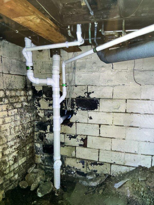Completed full replacement of first floor bathroom group drain line system over a two-day period. Removed existing deteriorated drainage piping and installed new PVC drain lines to all fixtures, including a new closet flange for the toilet. Work involved removing and reinstalling the toilet, running new branch lines to each fixture, and ensuring proper venting and drainage slope throughout the system. All connections were properly fitted and secured with appropriate brackets and supports to structural members in the basement area. System was tested for proper flow and verified leak-free operation upon completion.