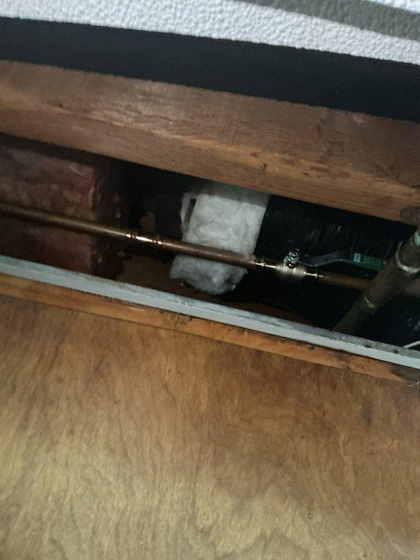 Responded to water leak emergency where a 20-year-old toilet was actively leaking through the basement ceiling. Upon arrival, water supply to the toilet had already been shut off by the customer to prevent further damage. Inspected the affected area, including crawl space access point, and documented copper supply line configuration and surrounding structural components showing signs of water exposure and corrosion. Photos captured the plumbing infrastructure, pipe routing, and insulation in the affected ceiling cavity to assess leak source and extent of damage.