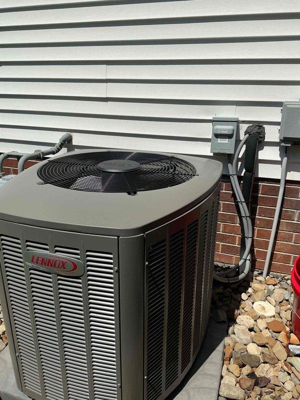 Responded to service call for non-operational air conditioning system affecting entire home. Upon arrival, inspected 4-year-old Lennox condensing unit located on exterior concrete pad with proper clearances and landscaping. Unit remained under manufacturer warranty from original installation. Performed comprehensive diagnostic evaluation of outdoor condenser including visual inspection of housing, louvered panels, and fan assembly. Checked electrical disconnect box and conduit connections mounted on building exterior. Verified refrigerant line sets running from condenser to structure showed no visible damage or degradation. Assessed unit positioning on concrete pad and surrounding river rock landscaping for proper drainage and airflow clearance. Documented equipment condition and installation configuration with photographs for warranty claim processing and service records. System required warranty service authorization to proceed with necessary repairs.