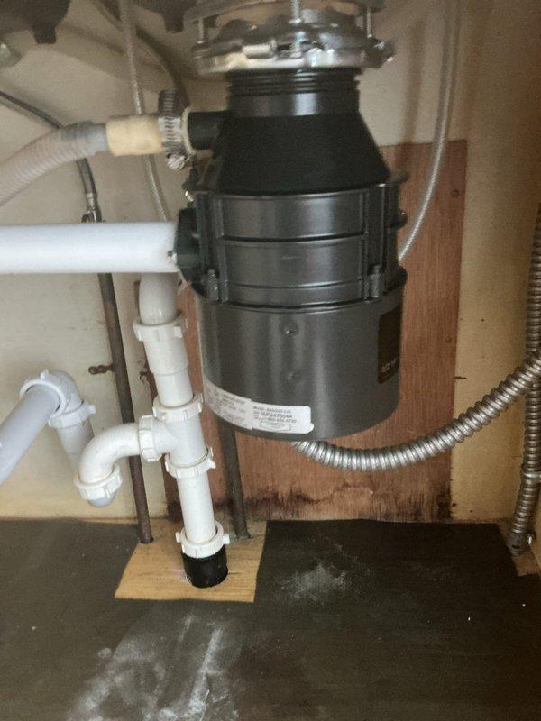 Completed full-day plumbing service including replacement of kitchen garbage disposal unit with new disposal connected to existing drain system via PVC P-trap configuration. Replaced three-handle tub and shower valve assembly with crystal-style handles mounted on chrome bases against tile wall. Installed whole house water filtration system positioned downstream of existing water softener to provide comprehensive water treatment. Cleared obstruction from bathtub drain to restore proper drainage flow.