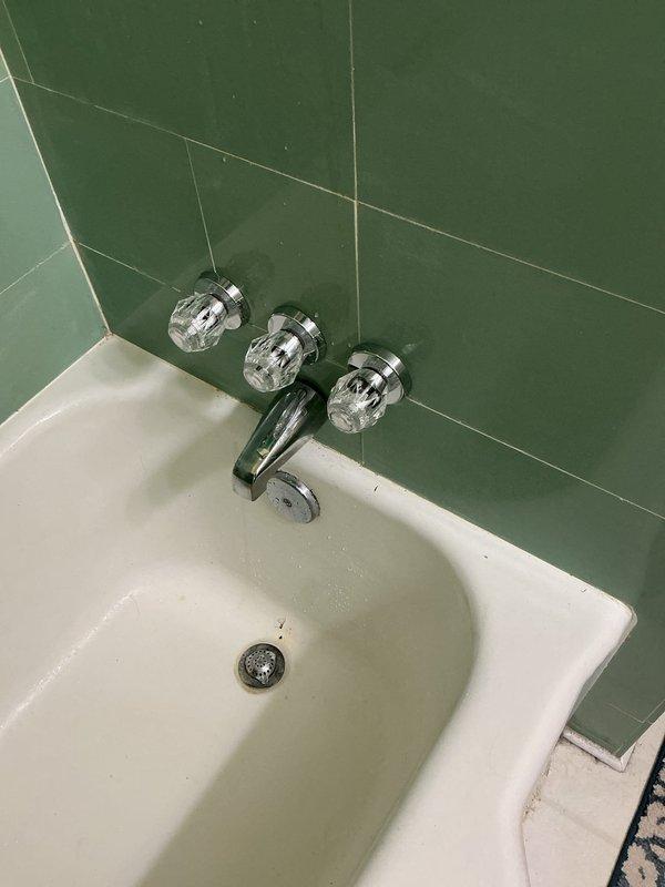Completed full-day plumbing service including replacement of kitchen garbage disposal unit with new disposal connected to existing drain system via PVC P-trap configuration. Replaced three-handle tub and shower valve assembly with crystal-style handles mounted on chrome bases against tile wall. Installed whole house water filtration system positioned downstream of existing water softener to provide comprehensive water treatment. Cleared obstruction from bathtub drain to restore proper drainage flow.