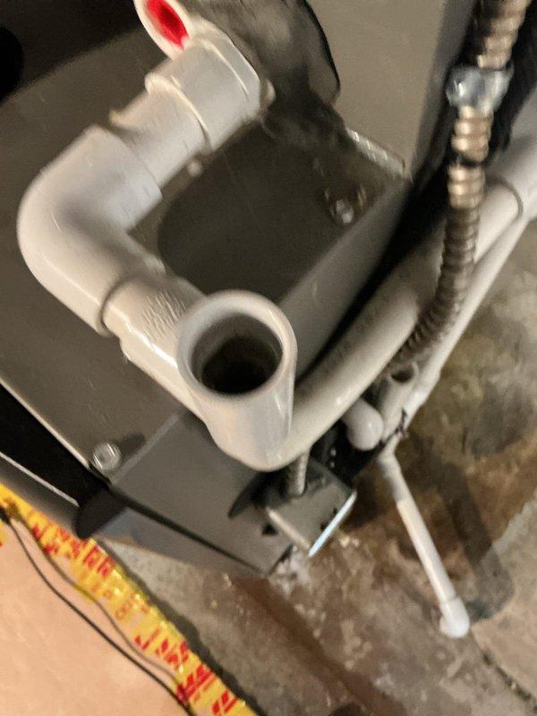 Responded to service call for 3-year-old air conditioning system with water leakage near filter area in basement. Upon inspection, identified issue with condensate drain assembly and pump mechanism. Examined all PVC drainage connections, flexible condensate lines, and drain pan assembly for proper operation and potential blockages. Documented existing plumbing configuration including multiple drain line connections and condensate pump housing to ensure proper drainage function and prevent future water leakage in the area.