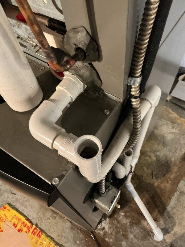 Responded to service call for 3-year-old air conditioning system with water leakage near filter area in basement. Upon inspection, identified issue with condensate drain assembly and pump mechanism. Examined all PVC drainage connections, flexible condensate lines, and drain pan assembly for proper operation and potential blockages. Documented existing plumbing configuration including multiple drain line connections and condensate pump housing to ensure proper drainage function and prevent future water leakage in the area.