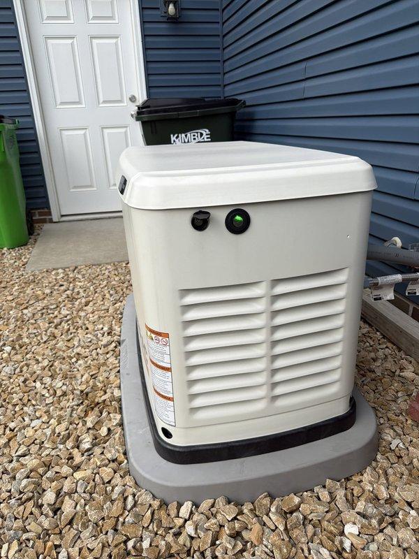 Completed annual preventive maintenance on residential Generac standby generator per manufacturer specifications. Performed comprehensive system inspection including visual examination of unit exterior, verified proper mounting and gravel pad placement, confirmed adequate clearances from structure, and checked for any signs of physical damage or deterioration. Tested battery voltage and condition using electronic battery analyzer, confirming "GOOD BATTERY" status with acceptable voltage levels. Inspected all external components including housing integrity, ventilation louvers for obstructions, and verified operational status indicators displaying proper green light illumination. Unit found to be in excellent operating condition with no issues identified. Generator is functioning properly and ready for automatic operation when required.