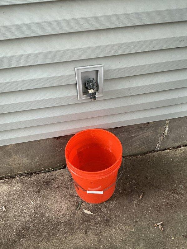 Responded to service call for leaking outdoor spigot at a 50-year-old residential property. Upon arrival, assessed the exterior hose bib and associated plumbing connections. Documented existing water meter assembly in basement with shutoff valves showing signs of age and corrosion. Inspected outdoor spigot mounted on exterior vinyl siding and identified source of leak. Photographed plumbing infrastructure including water meter, shutoff valves, and exterior fixture for estimate preparation. Provided detailed assessment and repair recommendations to address the leaking outdoor spigot.