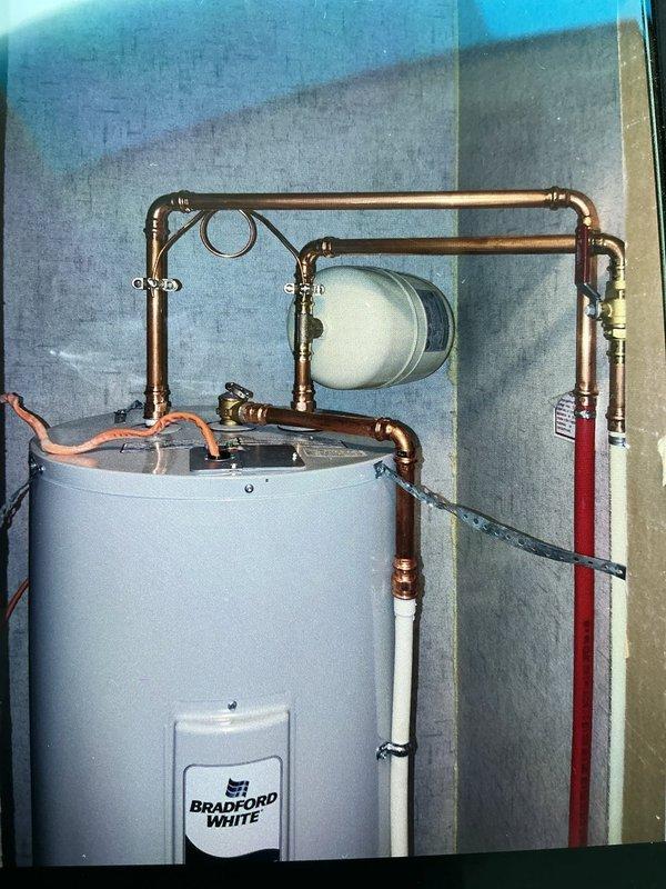 Replaced existing water heater with new Bradford White 40-gallon electric tank water heater in residential utility area. Installation included required code upgrades: installed thermal expansion tank on cold water supply line and new water shut-off valve. Configured copper piping system with proper connections, brass fittings, and shut-off valves throughout. Installed drain pan beneath unit for leak protection. Completed all electrical connections and verified proper operation of new system with 6-year warranty coverage.