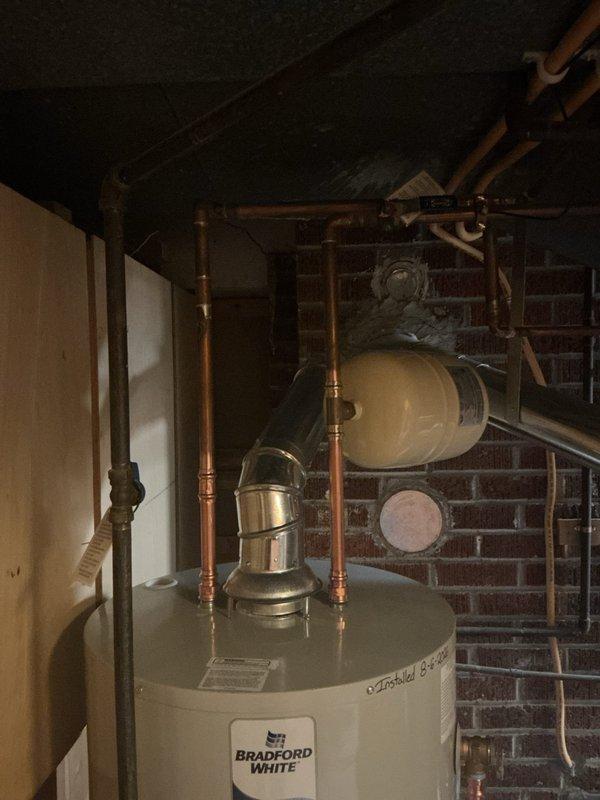Removed existing Bradford White residential water heater and installed new replacement unit in basement utility area. Installation included all necessary copper piping connections to integrate with existing plumbing system. Added thermal expansion tank to bring installation into compliance with current plumbing code requirements. New water heater includes 6-year manufacturer warranty and was installed against exposed brick wall with proper clearances maintained. All connections pressure-tested and verified operational upon completion.