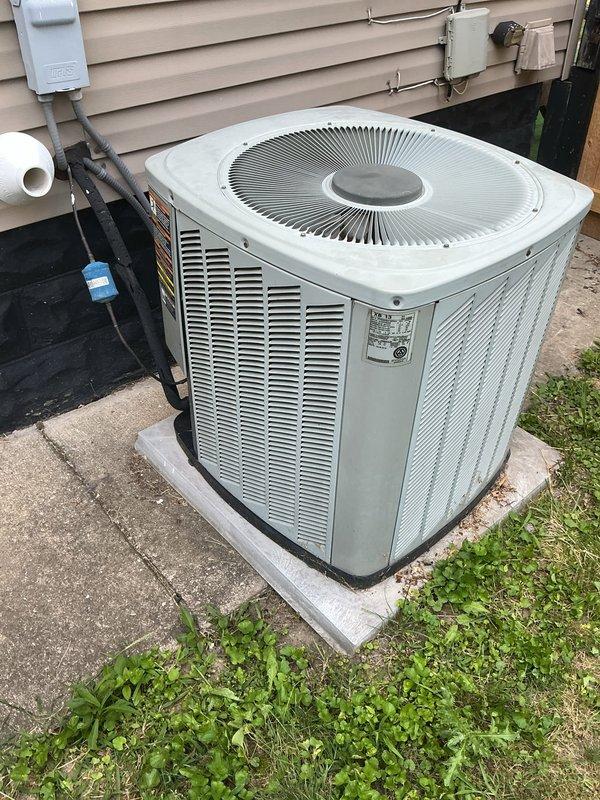 Responded to service call for 20-year-old air conditioning system with inadequate cooling performance and suspected refrigerant leak. Upon arrival, performed visual inspection of outdoor condenser unit and documented equipment condition. Unit showed signs of age-appropriate wear with vegetation growth around base and weathered concrete pad. Verified electrical connections and conduit routing to disconnect box. Assessed overall system operation and identified need for further diagnostic testing to determine refrigerant levels and locate potential leak points in aging system.