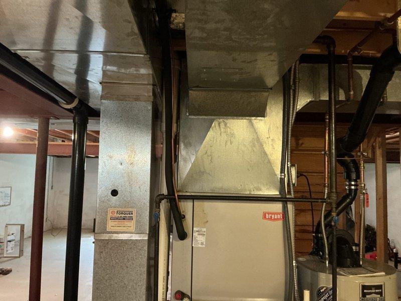Conducted comprehensive site assessment for furnace and air conditioning system replacement. Evaluated existing Bryant furnace installation in basement mechanical room, documenting current ductwork configuration, plenum connections, and overall HVAC infrastructure condition. Inspected exterior condensing unit location and surrounding utility area, noting drainage conditions and clearance requirements for new equipment installation.