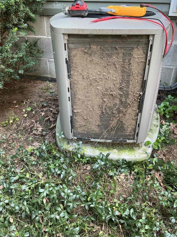 Responded to service call for 2018 Lennox system with non-operational outdoor unit while indoor unit continued running but providing insufficient cooling to residence. Upon arrival, performed diagnostic assessment of outdoor condenser unit and discovered heavily soiled evaporator coil with significant accumulation of dirt, dust, and debris restricting airflow. Opened access panel and documented condition of coil surface showing thick, uniform buildup that had developed over extended period. Utilized multimeter and testing equipment to verify electrical connections and system functionality at outdoor disconnect and control panel. Inspected wiring harness, terminals, and electrical components for proper operation. Noted vegetation growth in close proximity to unit and natural debris accumulation around equipment. Assessed flexible conduit lines and overall installation condition during troubleshooting process.