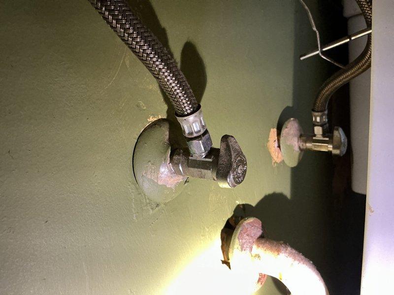 Installed two bathroom faucets in a century-old home with aging plumbing infrastructure. Removed existing corroded fixtures showing significant mineral buildup and rust deterioration around wall penetrations. Connected new faucets using flexible braided supply lines to existing copper stub-outs, addressing water staining and corrosion issues at connection points to ensure proper sealing and prevent future leakage.