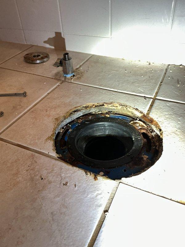Replaced first floor bathroom toilet with new American Standard Champion elongated chair height model. Removed existing deteriorated toilet and addressed severely corroded toilet flange exhibiting extensive rust staining and deterioration around drain opening. Installed new toilet flange assembly with proper sealing components to ensure watertight connection. Installed new water supply shut-off valve to bring fixture up to current plumbing standards. Completed full toilet installation with all necessary hardware, mounting bolts, and wax ring seal. Tested system for proper operation and verified no leaks at flange connection or supply line.