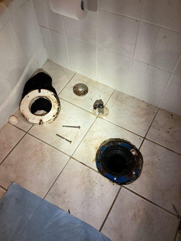 Replaced first floor bathroom toilet with new American Standard Champion elongated chair height model. Removed existing deteriorated toilet and addressed severely corroded toilet flange exhibiting extensive rust staining and deterioration around drain opening. Installed new toilet flange assembly with proper sealing components to ensure watertight connection. Installed new water supply shut-off valve to bring fixture up to current plumbing standards. Completed full toilet installation with all necessary hardware, mounting bolts, and wax ring seal. Tested system for proper operation and verified no leaks at flange connection or supply line.
