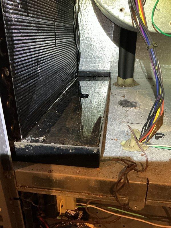 # Geothermal Unit Non-Operational - Moisture Issue Resolved

Responded to service call for non-operational 11-year-old geothermal heat pump system. Upon arrival, performed comprehensive system diagnostic and visual inspection of air handler and evaporator coil assembly.

Inspection revealed excessive condensation and moisture accumulation throughout the air handler cabinet and on surrounding surfaces. Heavy water droplets observed on cabinet walls with visible streaking and pooling on the drip pan and mounting platform. The evaporator coil showed signs of prolonged moisture exposure with debris accumulation on the base platform. Multiple surfaces exhibited water damage consistent with drainage system failure or inadequate condensate removal.

Examined the corrugated flexible ductwork connection and cabinet sealing at the unit junction. Identified compromised condensate drainage as primary cause of system shutdown. The moisture accumulation indicated either a clogged condensate line, fa