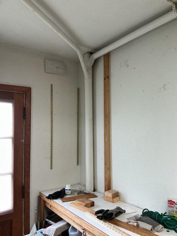 Responded to emergency call for exposed and broken water line. Upon arrival, assessed damage to interior water supply pipe running vertically along corner wall in utility/workshop area. Pipe showed signs of failure with visible exposure requiring immediate attention. Exterior inspection revealed related water damage to building soffit area with significant deterioration, exposed insulation, and water staining indicating ongoing leak penetration through building envelope. Documented extensive damage to both interior plumbing system and exterior structural components. Identified compromised soffit panels and water-damaged insulation requiring coordination with additional trades for complete remediation. Provided customer with assessment of damaged water line and recommended immediate repair to prevent further water intrusion and structural deterioration.