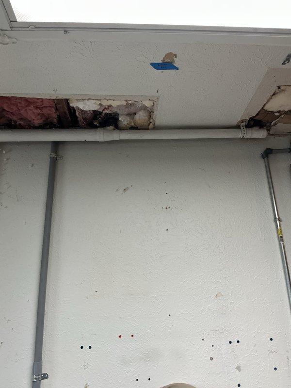 Responded to emergency call for exposed and broken water line. Upon arrival, assessed damage to interior water supply pipe running vertically along corner wall in utility/workshop area. Pipe showed signs of failure with visible exposure requiring immediate attention. Exterior inspection revealed related water damage to building soffit area with significant deterioration, exposed insulation, and water staining indicating ongoing leak penetration through building envelope. Documented extensive damage to both interior plumbing system and exterior structural components. Identified compromised soffit panels and water-damaged insulation requiring coordination with additional trades for complete remediation. Provided customer with assessment of damaged water line and recommended immediate repair to prevent further water intrusion and structural deterioration.