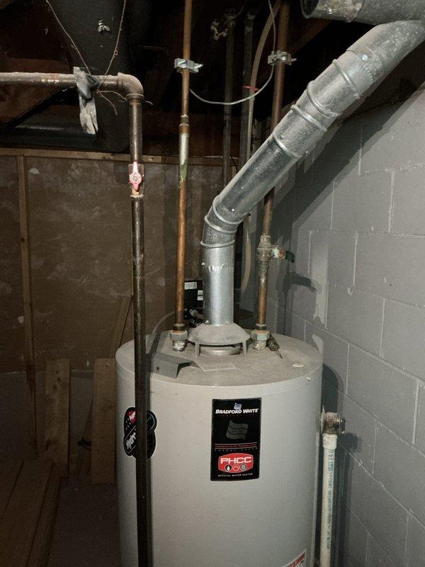 Completed preventative maintenance service including comprehensive whole-home plumbing inspection and water heater flush on Bradford White tanked unit located in basement utility area. Performed systematic drain and flush procedure to remove sediment buildup from tank, inspected all visible copper supply lines, compression fittings, and shutoff valves for proper operation and signs of corrosion or leaks. Verified temperature and pressure relief valve functionality, examined anode rod condition, and confirmed proper venting through insulated ductwork. Inspected exposed plumbing throughout mechanical room including vertical black iron drain lines and PVC drainage systems for structural integrity. All components found operating within normal parameters with no immediate concerns identified; unit refilled and returned to service with no issues noted.