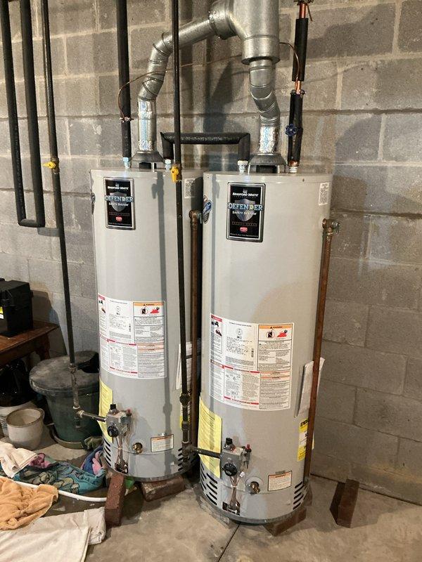 Replaced two 18-year-old residential water heaters with new Defender brand tanked units after one failed and the homeowner elected to replace both due to age. Removed existing equipment, installed two new water heaters side by side in basement utility room, connected all supply and discharge piping, installed proper venting with metallic ductwork routed to existing chimney or vent system, installed safety relief valves with discharge piping, connected gas lines with shut-off valves, tested all connections for leaks, verified proper combustion and venting operation, and restored full hot water service throughout the residence.