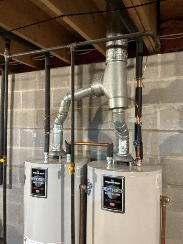 Replaced two 18-year-old residential water heaters with new Defender brand tanked units after one failed and the homeowner elected to replace both due to age. Removed existing equipment, installed two new water heaters side by side in basement utility room, connected all supply and discharge piping, installed proper venting with metallic ductwork routed to existing chimney or vent system, installed safety relief valves with discharge piping, connected gas lines with shut-off valves, tested all connections for leaks, verified proper combustion and venting operation, and restored full hot water service throughout the residence.