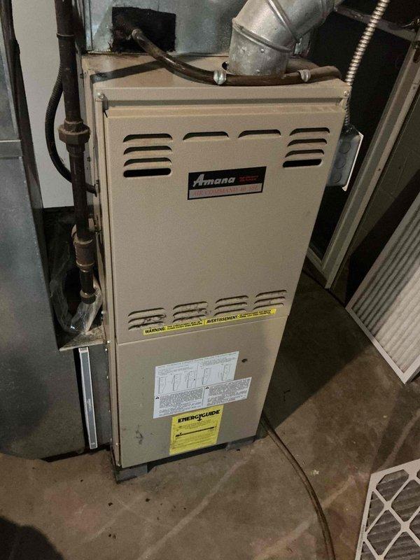 Responded to service call for loud groaning noise occurring when blower motor engages on 24-year-old air conditioning system with 28-year-old Amana furnace. Upon arrival, performed diagnostic inspection of the HVAC system located in utility closet. Examined furnace unit, blower assembly, ductwork connections, and associated mechanical components. Documented existing equipment condition including aged furnace with standard wear patterns consistent with equipment age. Assessed metallic ductwork, flexible ducting connections, and pipe routing for potential noise sources. Given the advanced age of both the air conditioning and furnace systems, identified blower motor bearings or motor mount as likely cause of groaning noise during fan operation, though further operational testing during cooling cycle would be required for definitive diagnosis.