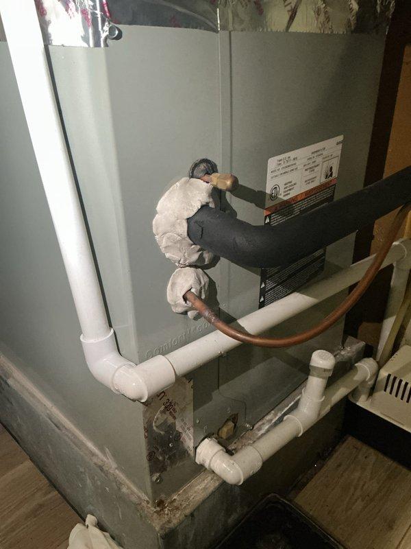 Responded to service call for water leak on 3-month-old furnace installation. Upon arrival, inspected unit and discovered deteriorated insulation on refrigerant line connections and evidence of condensate drainage issues based on water staining visible on concrete floor beneath equipment. Documented existing conditions with photographs showing compromised pipe insulation and moisture damage. Assessed PVC condensate drain system and copper refrigerant lines for proper installation and function to identify source of reported water intrusion in closet area.