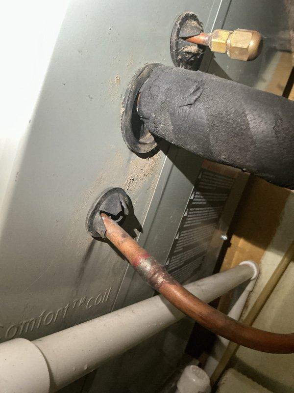 Responded to service call for water leak on 3-month-old furnace installation. Upon arrival, inspected unit and discovered deteriorated insulation on refrigerant line connections and evidence of condensate drainage issues based on water staining visible on concrete floor beneath equipment. Documented existing conditions with photographs showing compromised pipe insulation and moisture damage. Assessed PVC condensate drain system and copper refrigerant lines for proper installation and function to identify source of reported water intrusion in closet area.