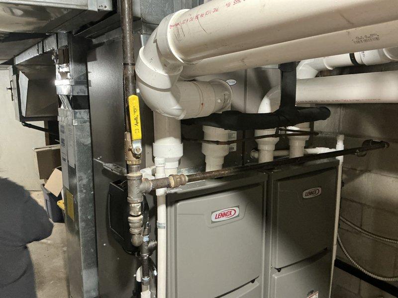 Completed air conditioning estimate for dual-zone system replacement in mechanical room with existing Lennox furnace units. Assessed current HVAC configuration including PVC condensate drainage network, ductwork connections, and equipment placement for recommended system upgrade.