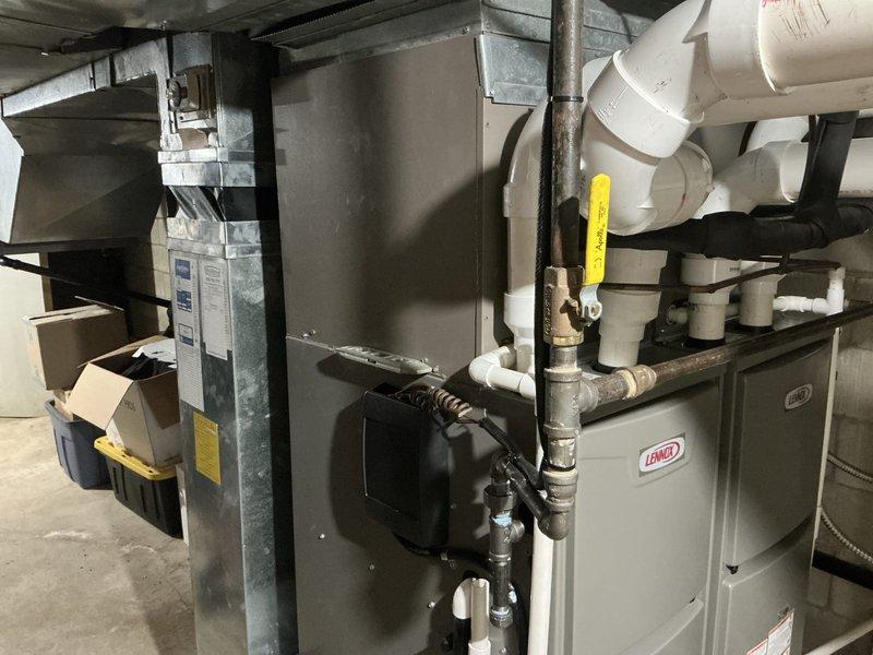 Completed air conditioning estimate for dual-zone system replacement in mechanical room with existing Lennox furnace units. Assessed current HVAC configuration including PVC condensate drainage network, ductwork connections, and equipment placement for recommended system upgrade.