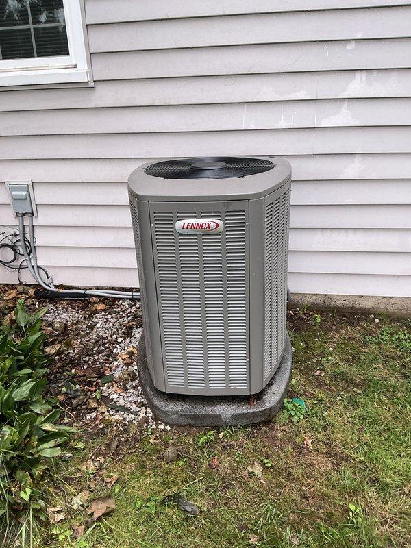 Responded to service call for 9-year-old Lennox central air conditioning system that had been physically displaced 8-10 inches by fallen tree branch and was no longer producing cold air. Upon arrival, found condenser unit sitting unlevel on concrete pad with potential damage from impact. Inspected refrigerant lines and confirmed both suction and liquid lines were ambient temperature, indicating loss of refrigeration cycle. Assessed unit positioning, checked for visible damage to cabinet, coil fins, and refrigerant line connections. Documented current condition of displaced unit with photographs showing unit against house exterior with visible offset from original position. System requires releveling, complete refrigerant leak check, potential line set inspection for kinks or damage, and full operational assessment once unit is properly repositioned and secured.