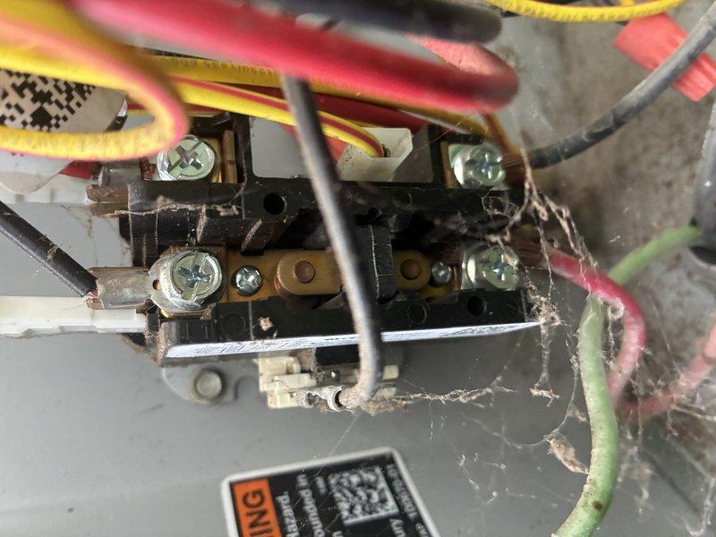 Completed BS-MVP recurring cooling maintenance visit on residential outdoor condenser unit. Performed standard system inspection, documenting electrical connections within control panel which showed normal operation despite accumulated dust and debris, and verified outdoor unit condition with heat exchanger coils and fan assembly functioning properly amid established landscaping.