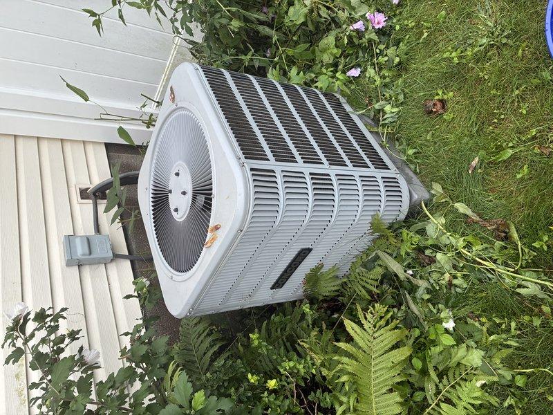 Completed BS-MVP recurring cooling maintenance visit on residential outdoor condenser unit. Performed standard system inspection, documenting electrical connections within control panel which showed normal operation despite accumulated dust and debris, and verified outdoor unit condition with heat exchanger coils and fan assembly functioning properly amid established landscaping.