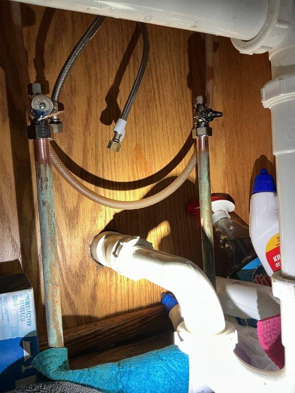 Responded to service call for leaking hot water supply line under kitchen sink. Upon arrival after 1pm per customer availability, inspected under-sink plumbing and identified leak at hot water supply connection. The existing copper supply lines showed significant corrosion and green patina buildup, indicating age-related deterioration. Shut off water supply at angle stop valves, removed defective hot water supply line, and installed new braided stainless steel flexible supply line with proper connections to both the angle stop valve and faucet tailpiece. Tested system for leaks, verified proper water flow, and confirmed repair was successful with no active leaks detected.