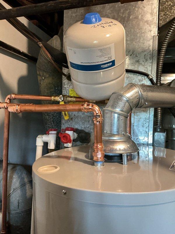 Installed a new 40-gallon Bradford White water heater with 6-year manufacturer warranty, including new ball valve, thermal expansion tank, and 1/4" shut-off valve for humidifier connection. Removed existing water heater and cut out old main water gate valve at meter location. Rebuilt main water line from meter with secondary ball valve installed after meter, installed new tee fitting for house water distribution, and ran complete copper piping to new water heater with proper fittings and connections. Water utility shut off supply at street curb to facilitate main line replacement work. All copper joints soldered, system pressure tested, and water heater commissioned for operation.
