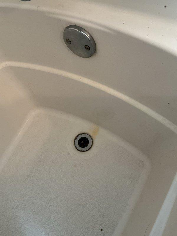 Responded to water leak complaint with visible ceiling damage below bathroom. Inspected bathtub and surrounding area with accessible access behind tub. Identified active leak originating from tub drain assembly causing water intrusion through ceiling below. Documented water staining on ceiling with concentrated moisture damage and discoloration. Photographed tub overflow plate, drain assembly, and affected ceiling area for record. Discussed repair options and membership program benefits with customer.