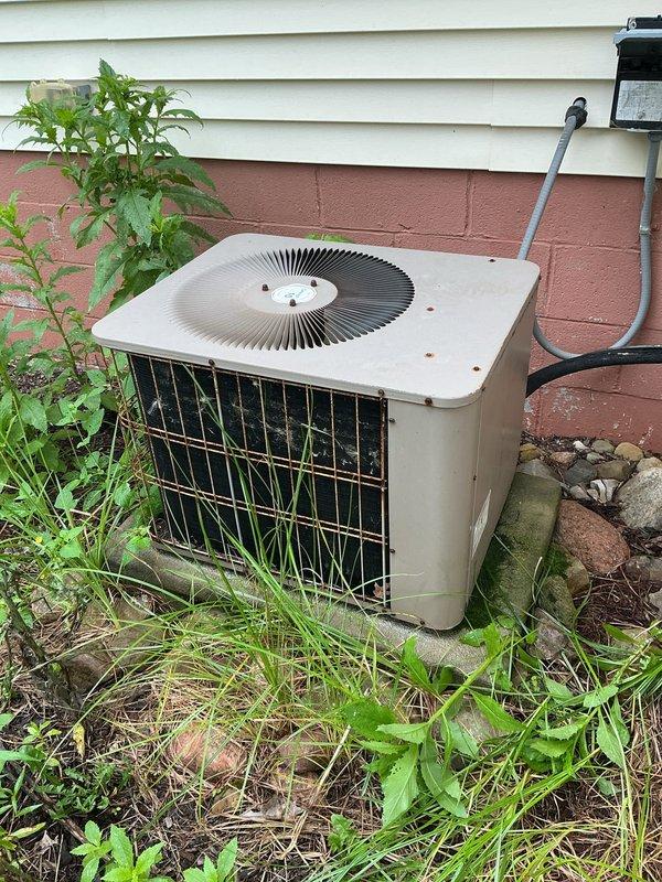 # HVAC Service Completed

Responded to no-cooling complaint on 10+ year old residential air conditioning system. Upon arrival, performed visual inspection of outdoor condensing unit and discovered severe neglect and environmental damage affecting system operation.

Found outdoor unit completely overgrown with vegetation at base, restricting airflow to lower intake areas. Removed access panels and discovered extensive accumulation of leaves, twigs, and decomposed organic debris throughout interior compartments. Debris had infiltrated both upper and lower sections of unit, blocking critical airflow pathways and covering electrical components and mechanical parts.

Observed significant deterioration of unit cabinet with advanced corrosion on metal frame and evidence of algae/mold growth on bottom sections due to prolonged moisture exposure. Electrical wiring remained intact but was obscured by debris. Compressor motor housing and connections showed weathering consistent with age and envir